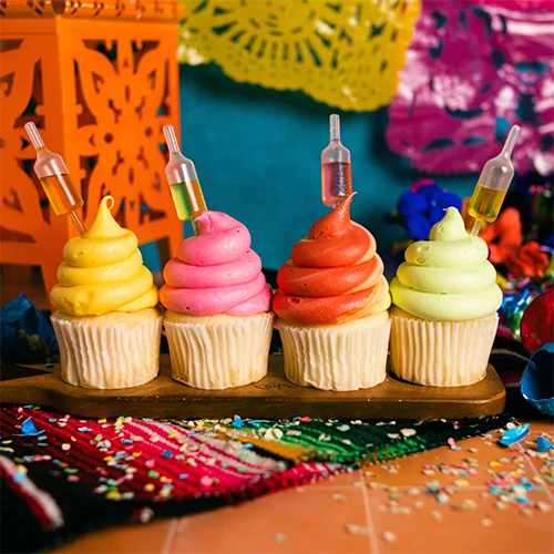 Decorations Bright colorful cupcakes with piped frosting and cake decorating syringes, set on a wooden tray with vibrant background decor. Perfect for celebration, cupcakes, cake supplies, and dessert decorating.