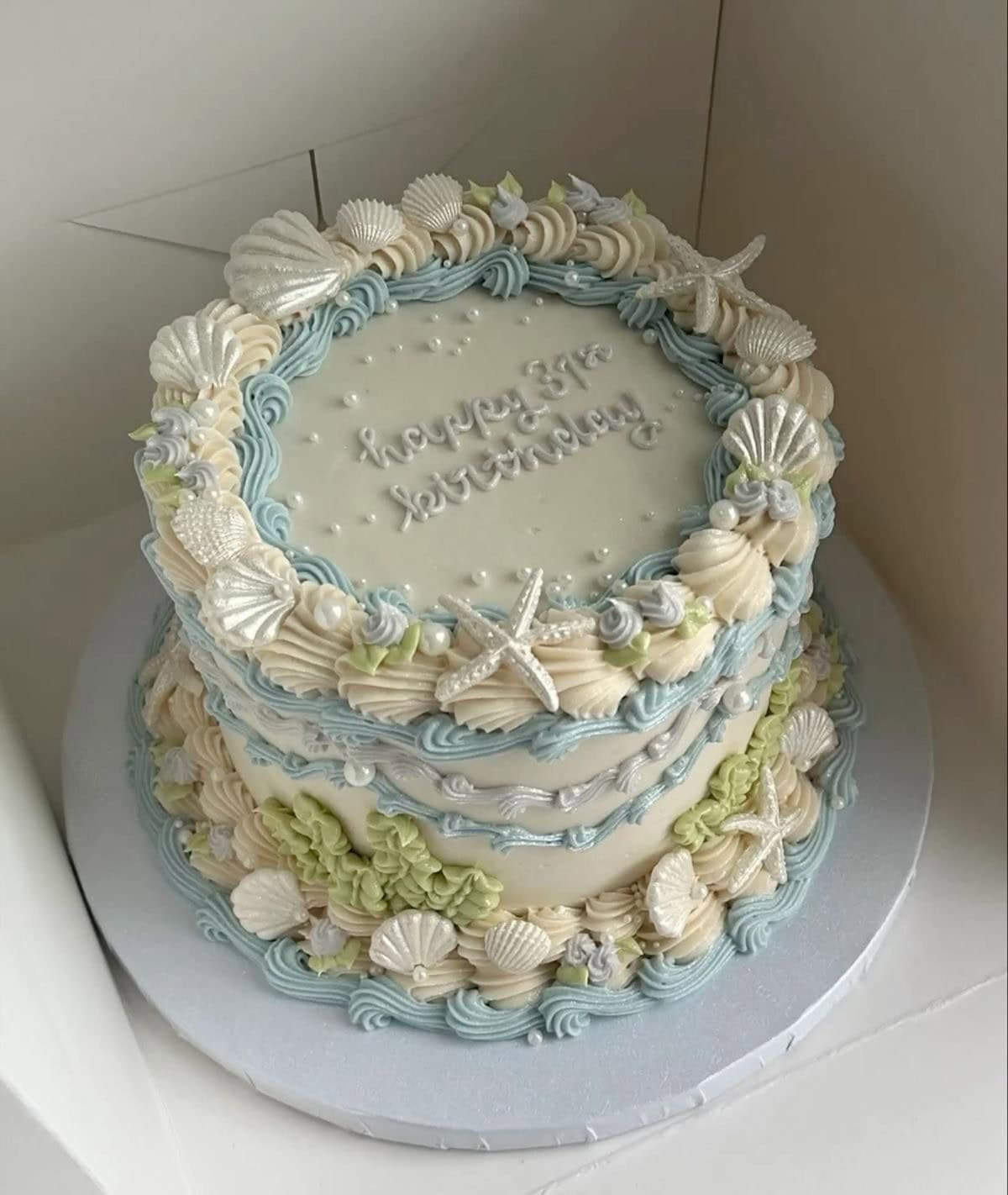 Beach-themed cake with shells and starfish decorations.