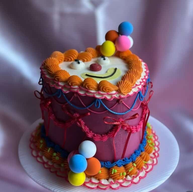 cute clown cake Colorful clown-themed cake with balloons on top.