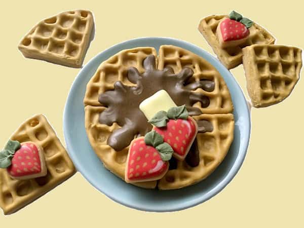 waffle cookie platter Waffles with strawberries, butter, and syrup on a plate.