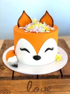 Bright fox-themed cake with fondant features, floral decorations, and realistic details, perfect for birthday parties or special celebrations.