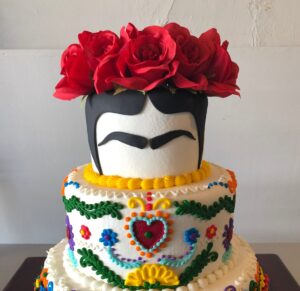 Vibrant Frida Kahlo inspired birthday cake with colorful sugar flowers, intricate piping, and a stylized face, perfect for celebrating artistic and cultural themes.