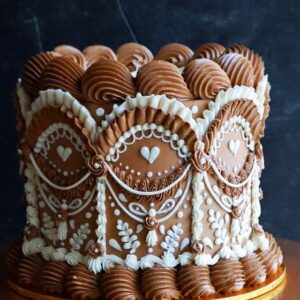 Decorative heart and floral patterned chocolate and vanilla wedding cake with piped icing ornaments, perfect for special celebrations.