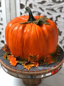Pumpkin cake decorated with realistic autumn leaves and stem, perfect for fall celebrations and Thanksgiving, showcasing professional cake decorating supplies from Over the Top Cake Supplies.