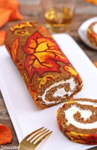 Colorful pumpkin spice cake roll with cream cheese filling, perfect for fall celebrations. Decorated with vibrant autumn-themed icing on cake from Over the Top Cake Supplies for homemade holiday desserts.