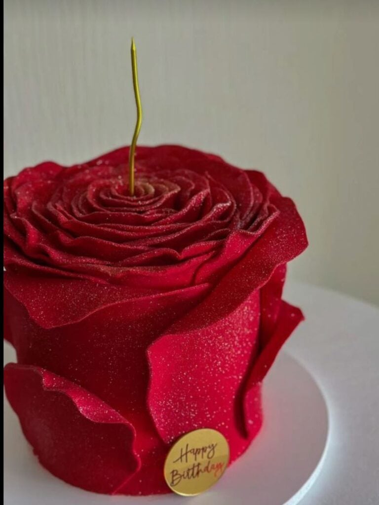 screenshot Red rose cake decorated with edible flower petals and glitter, suitable for birthday celebrations.