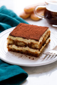 Chocolate tiramisu layered dessert on a white plate with cocoa powder, perfect for cake decorating and baking supplies from Over the Top Cake Supplies.