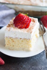 Rich vanilla cake with creamy frosting topped with fresh strawberries, perfect for celebrating special occasions.