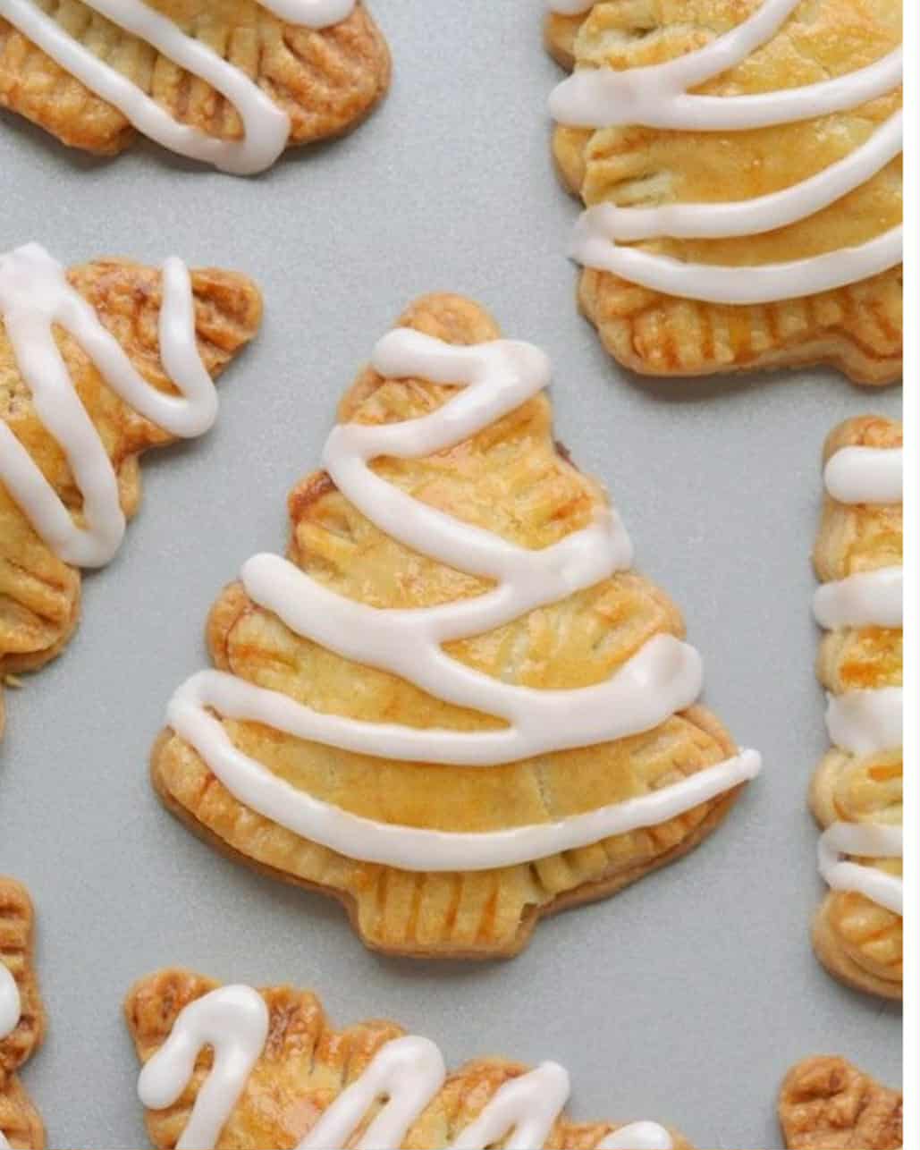 Butter cookies decorated as Christmas trees with white icing drizzle, perfect for holiday baking, catering, or dessert table displays.