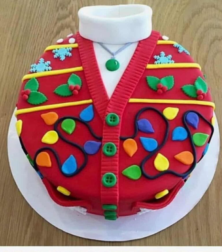 att.qssmb1hsdayfsrqk2f 4ulss0iyplnzbbuhohyl22hi Festive Christmas sweater cake decorated with colorful fondant lights, holly leaves, and buttons, perfect for holiday celebrations - Over the Top Cake Supplies.