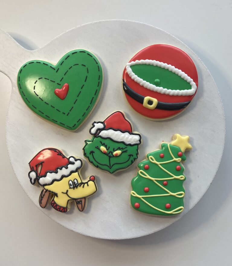 grinch cookies kimmie Colorful Christmas-themed decorated cookies, including a heart, Santa's belt, Grinch with Santa hat, dog wearing Santa hat, and a Christmas tree, perfect for holiday celebrations and cake decorating.