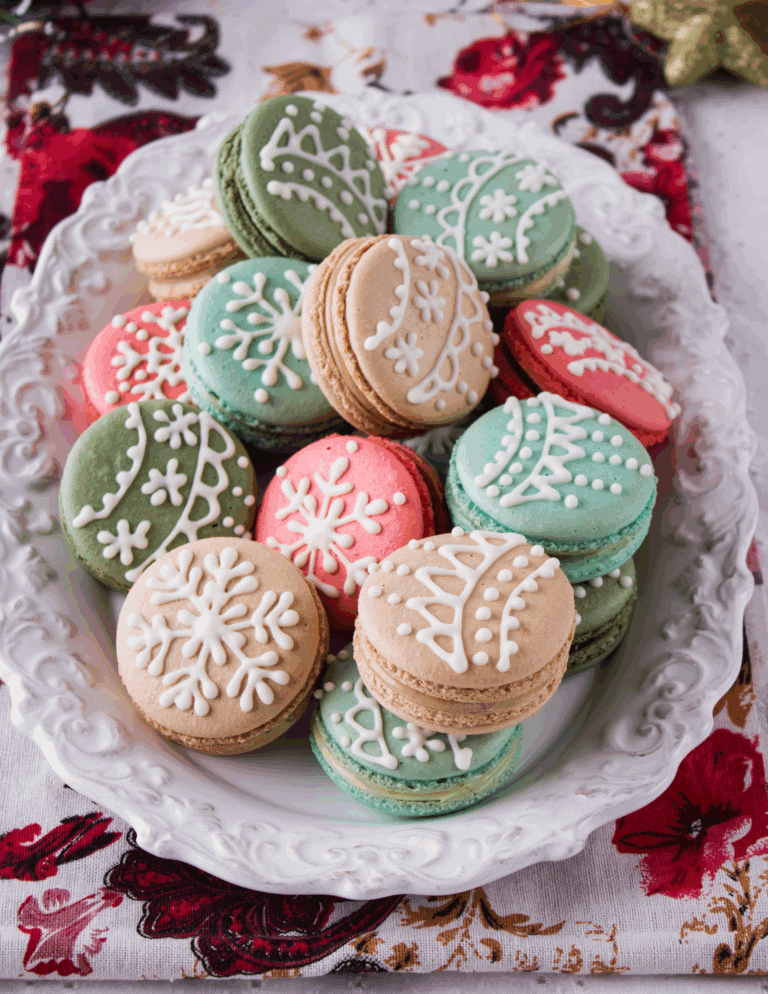 holiday macarons Colorful Christmas macarons decorated with white icing on a decorative white platter, ideal for holiday baking supplies and cake decorating.