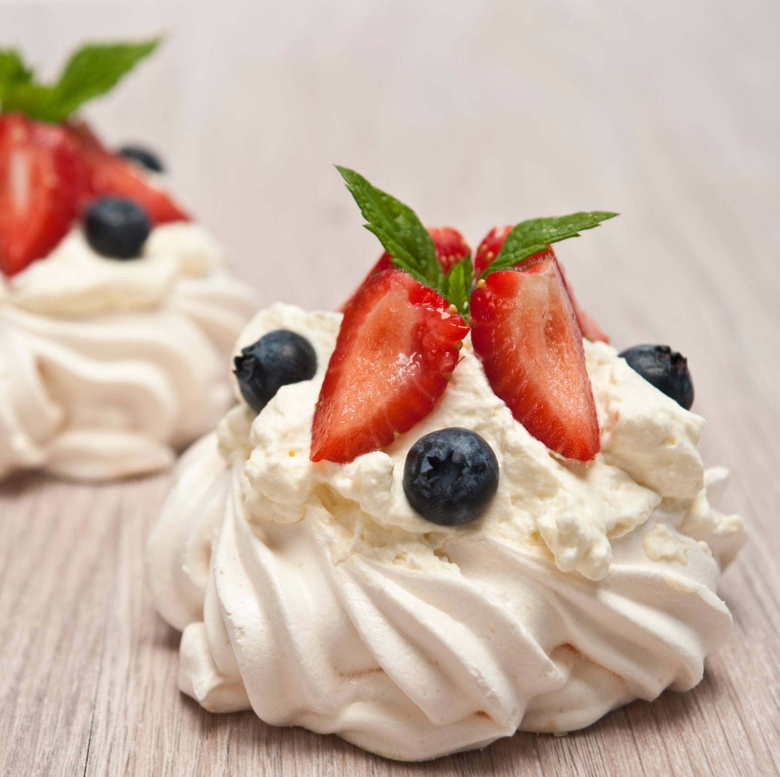 Fresh strawberries and blueberries decorated on whipped cream meringue cookies, perfect for cake and dessert decorating supplies.