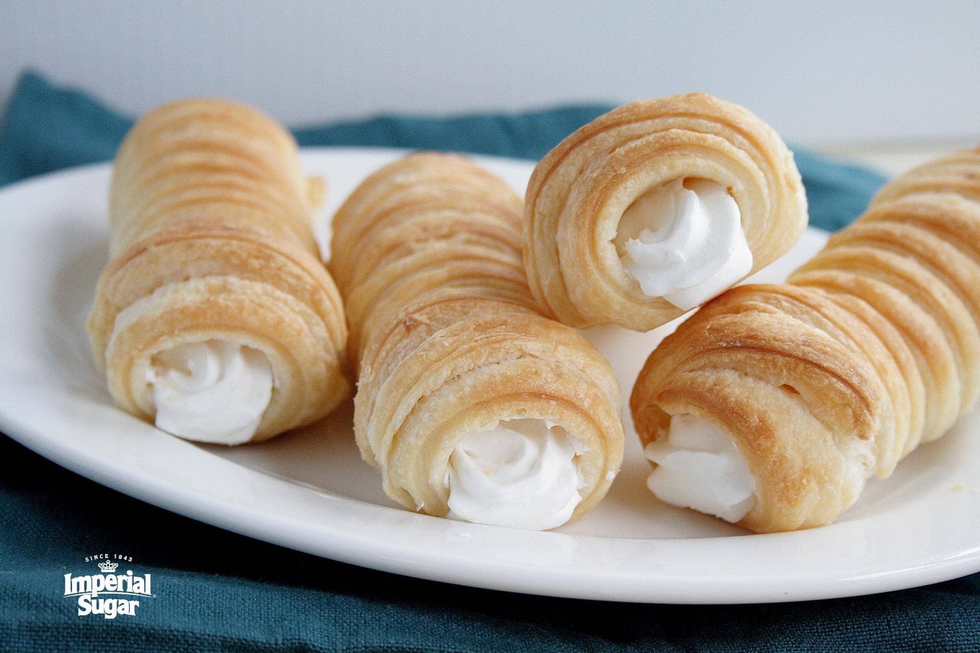Delicious cream-filled puff pastry cones on a white plate, perfect for bakery and confectionery outlets.