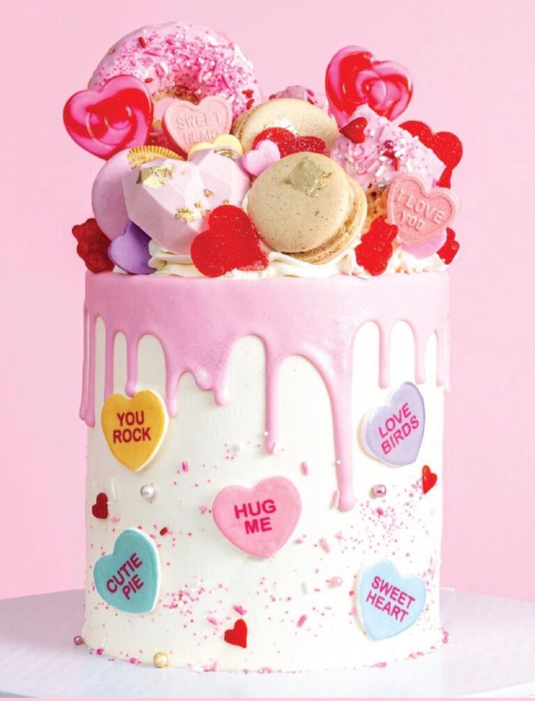 Bright pink Valentine's cake decorated with macarons, heart candies, and pink drizzle, perfect for romantic occasions. Ideal for cake decorating and bakery supply enthusiasts.