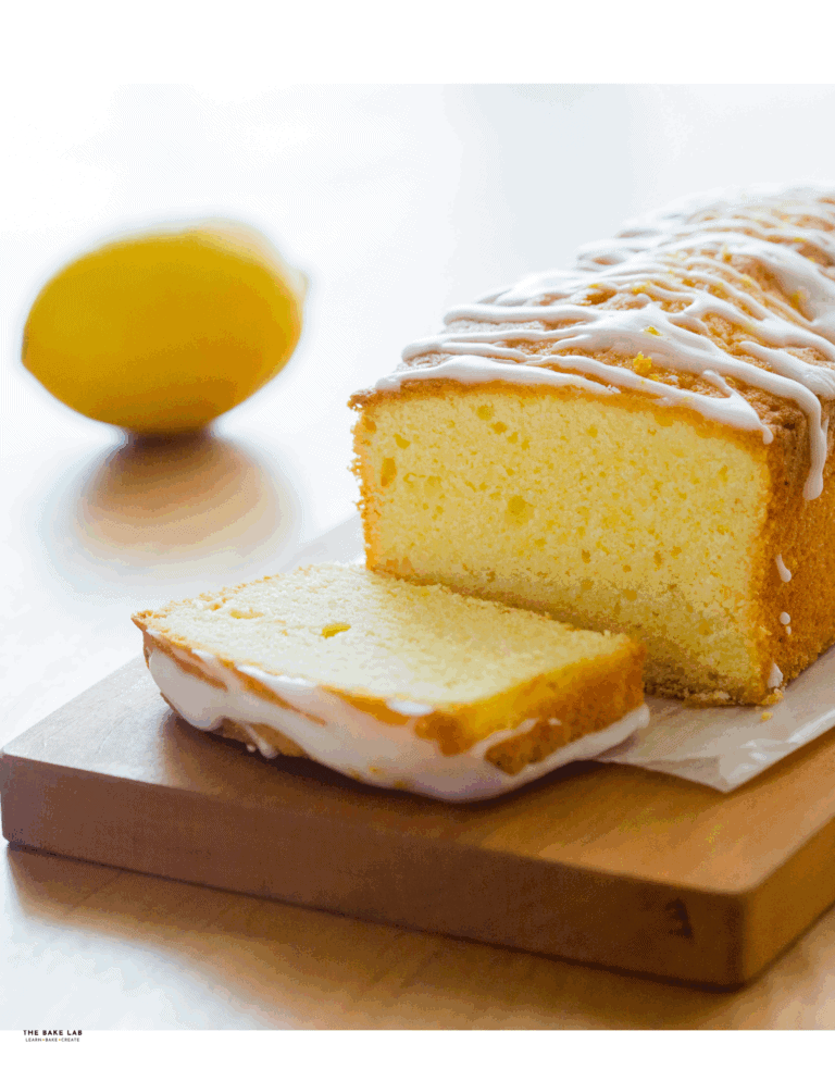 lemon drizzle cake Lemon cake loaf with lemon glaze on wooden board, fresh lemon in background, perfect for cake decorating and baking supplies.