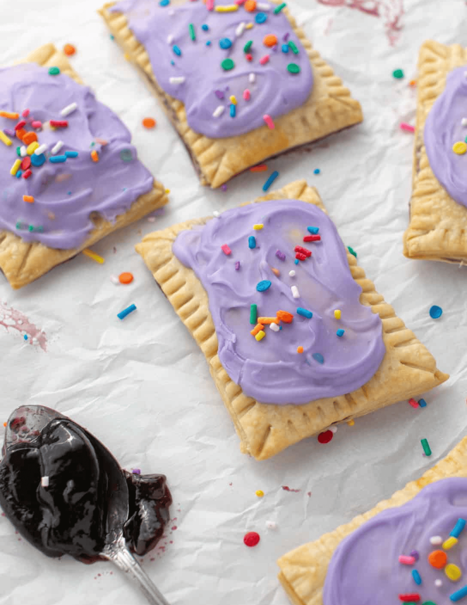 Colorful frosted cookies with sprinkles arranged on parchment paper, perfect for custom cake decorating supplies and baking ingredients.