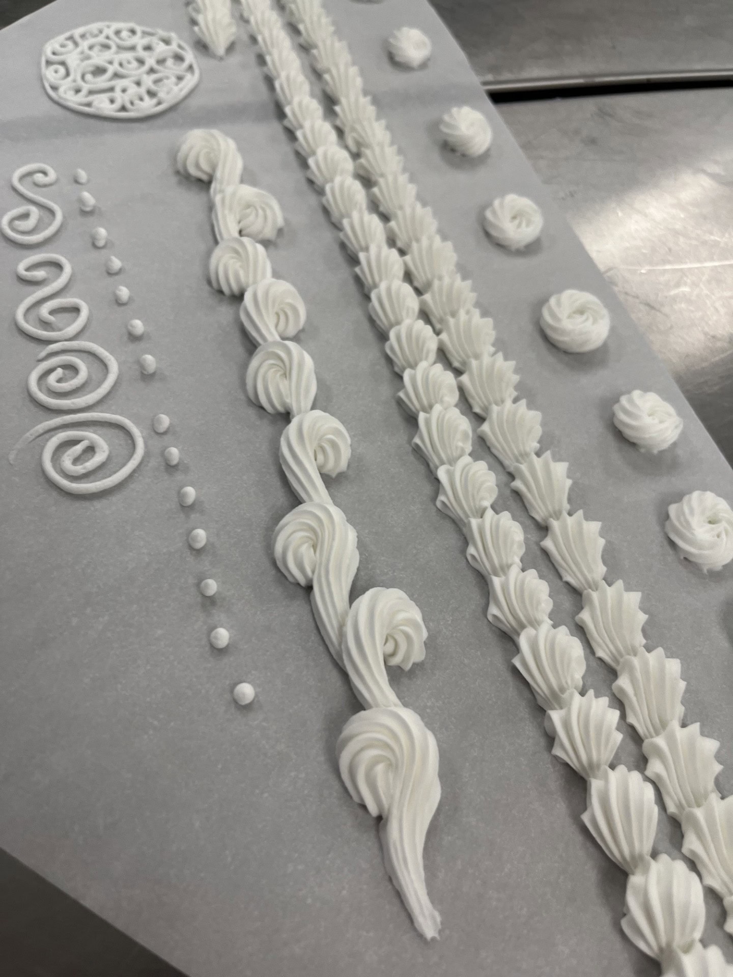 Delicate white piping gel and royal icing for cake decorating, showcasing intricate piping designs, shell motifs, and decorative borders for a professional cake finish.