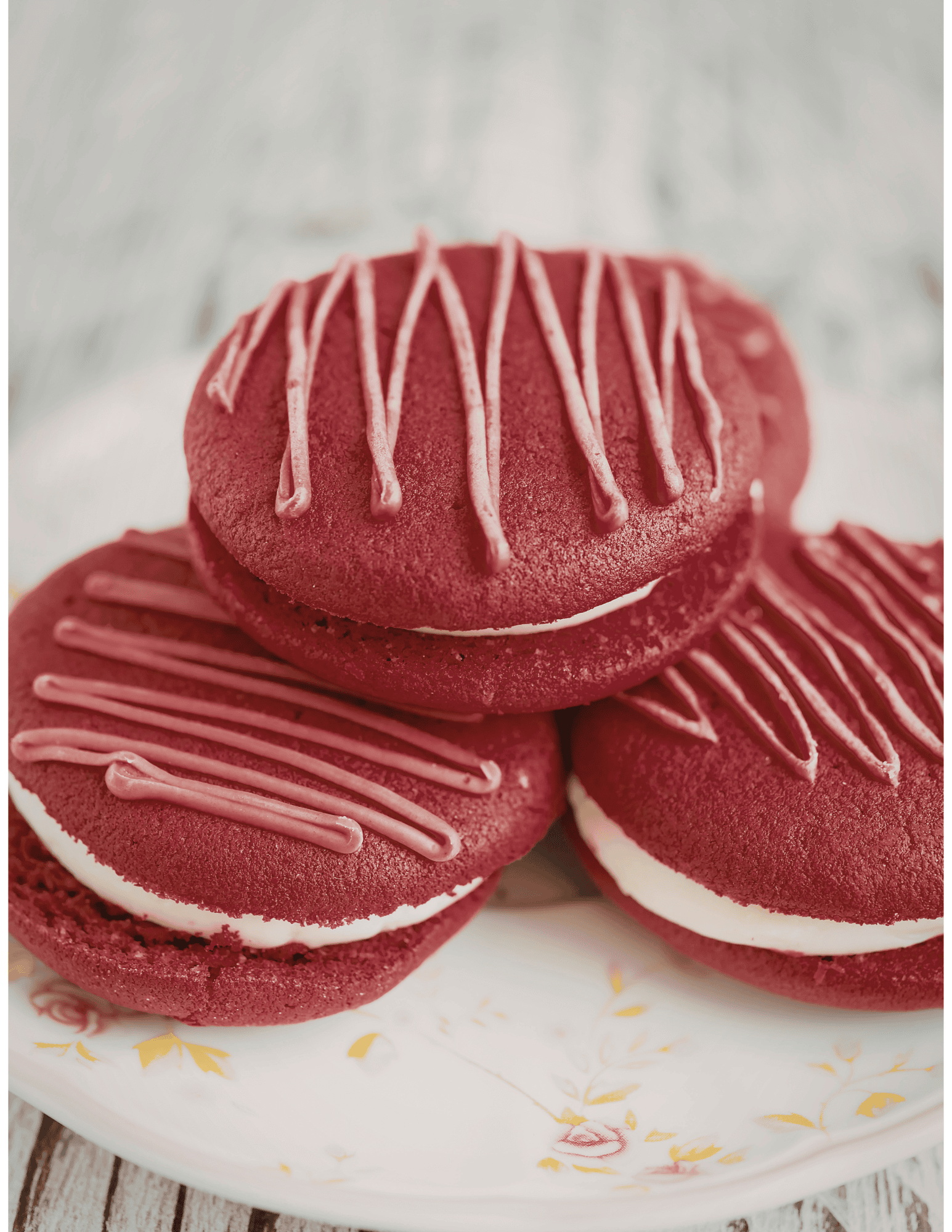 Delicious red velvet cookies with cream filling and pink drizzle, ideal for cake decorating and bakery supplies.