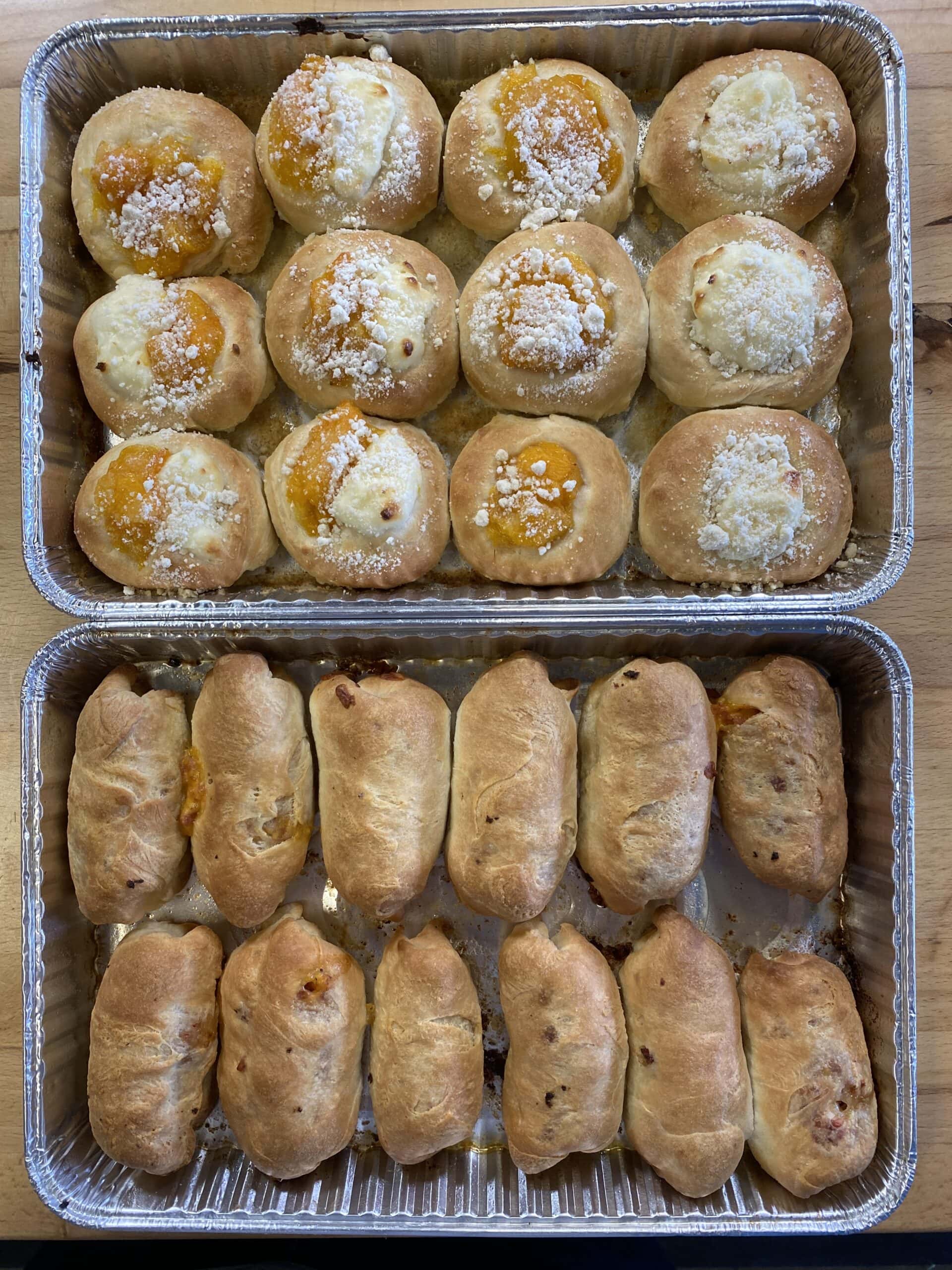 Delicious cream-filled pastries topped with powdered sugar and fruit preserves, ideal for bakery supplies, cakes, and dessert decorations.