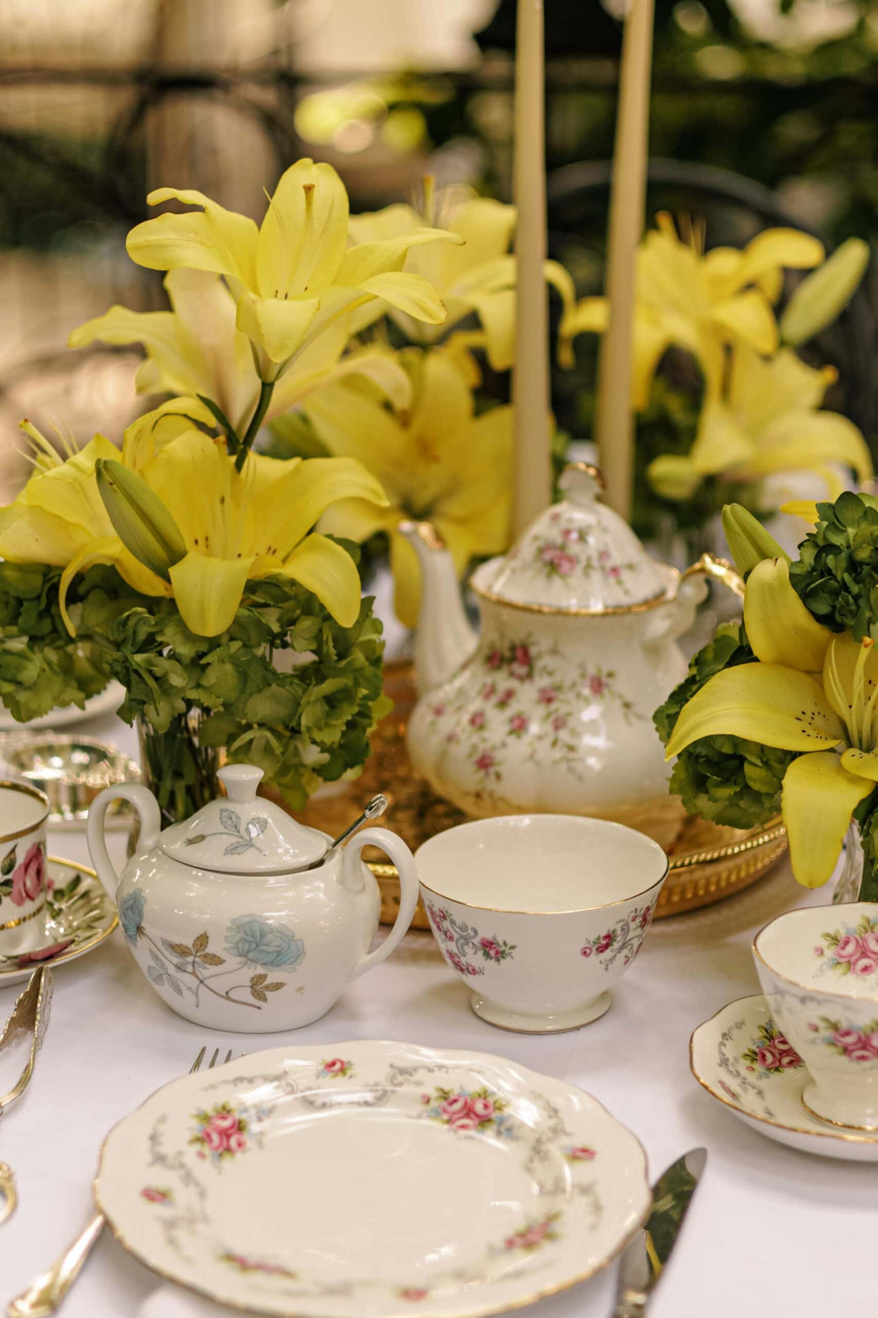 Beautiful porcelain teapot, cups, and saucers with floral designs and gold accents, perfect for wedding or tea party decor.