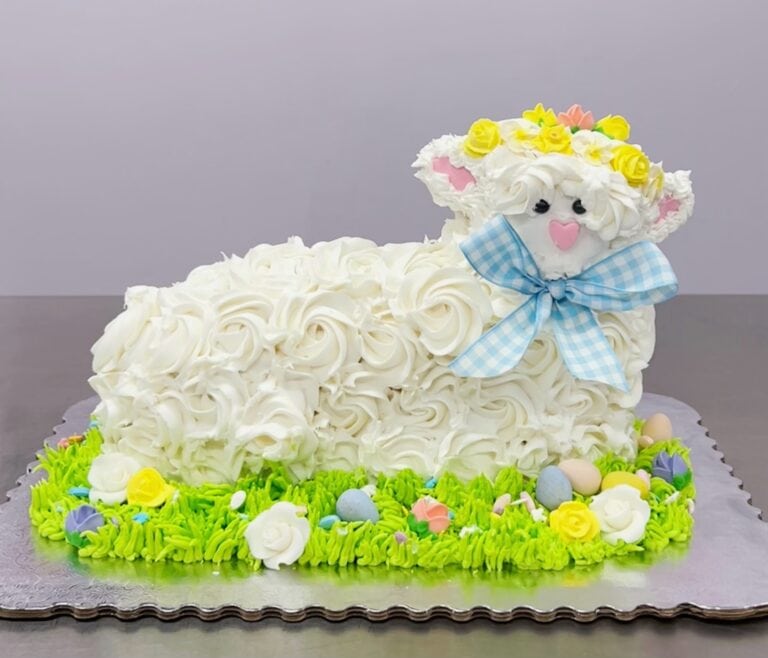 Easter Lamb Cake with Floral Decorations Easter lamb cake decorated with white frosting roses, colorful eggs, and a blue checkered bow, perfect for family celebrations and spring festivities.