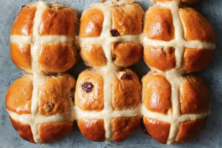 Freshly baked hot cross buns with golden-brown crust and white icing crosses, perfect for Easter or special occasions. Ideal for baking supplies and decorating.