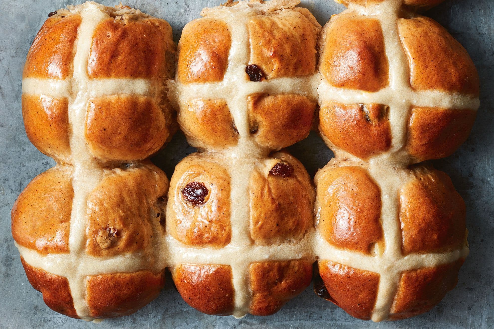 Freshly baked hot cross buns with golden-brown crust and white icing crosses, perfect for Easter or special occasions. Ideal for baking supplies and decorating.