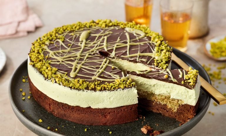 Delicious Dubai-style chocolate cheesecake topped with pistachios and white chocolate drizzle, perfect for cake decorating and dessert displays.
