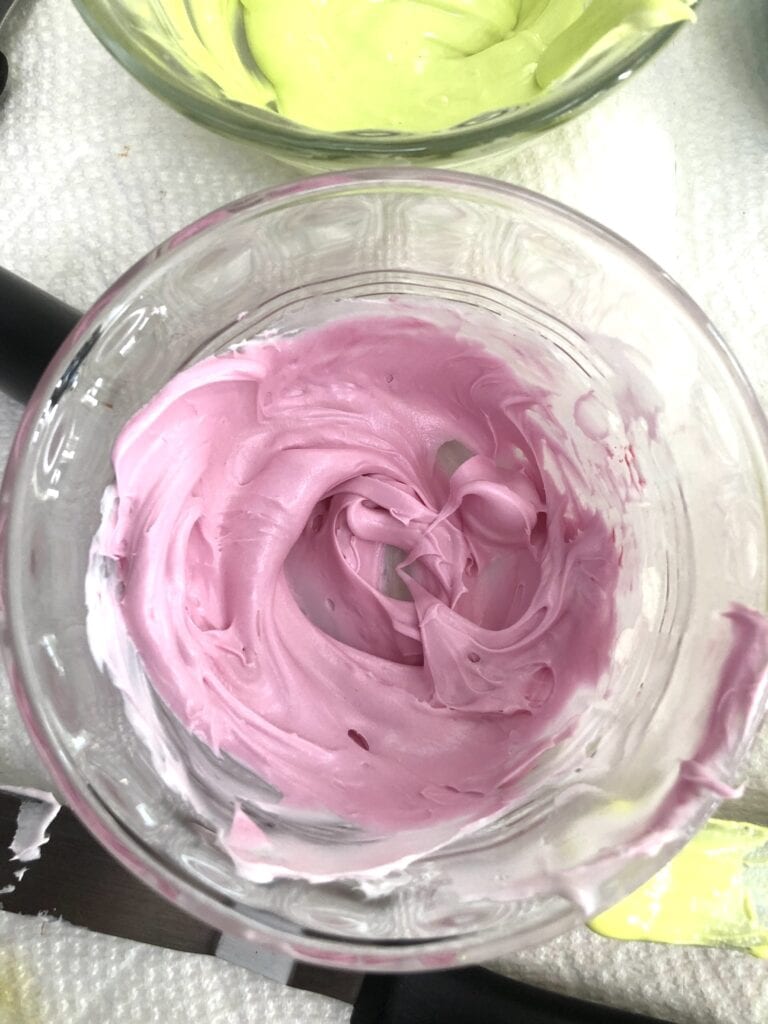 Pink Buttercream Icing for Cake Decorating Close-up of pink buttercream icing in a glass bowl, used for cake decorating, showcasing smooth, creamy texture and vibrant color.