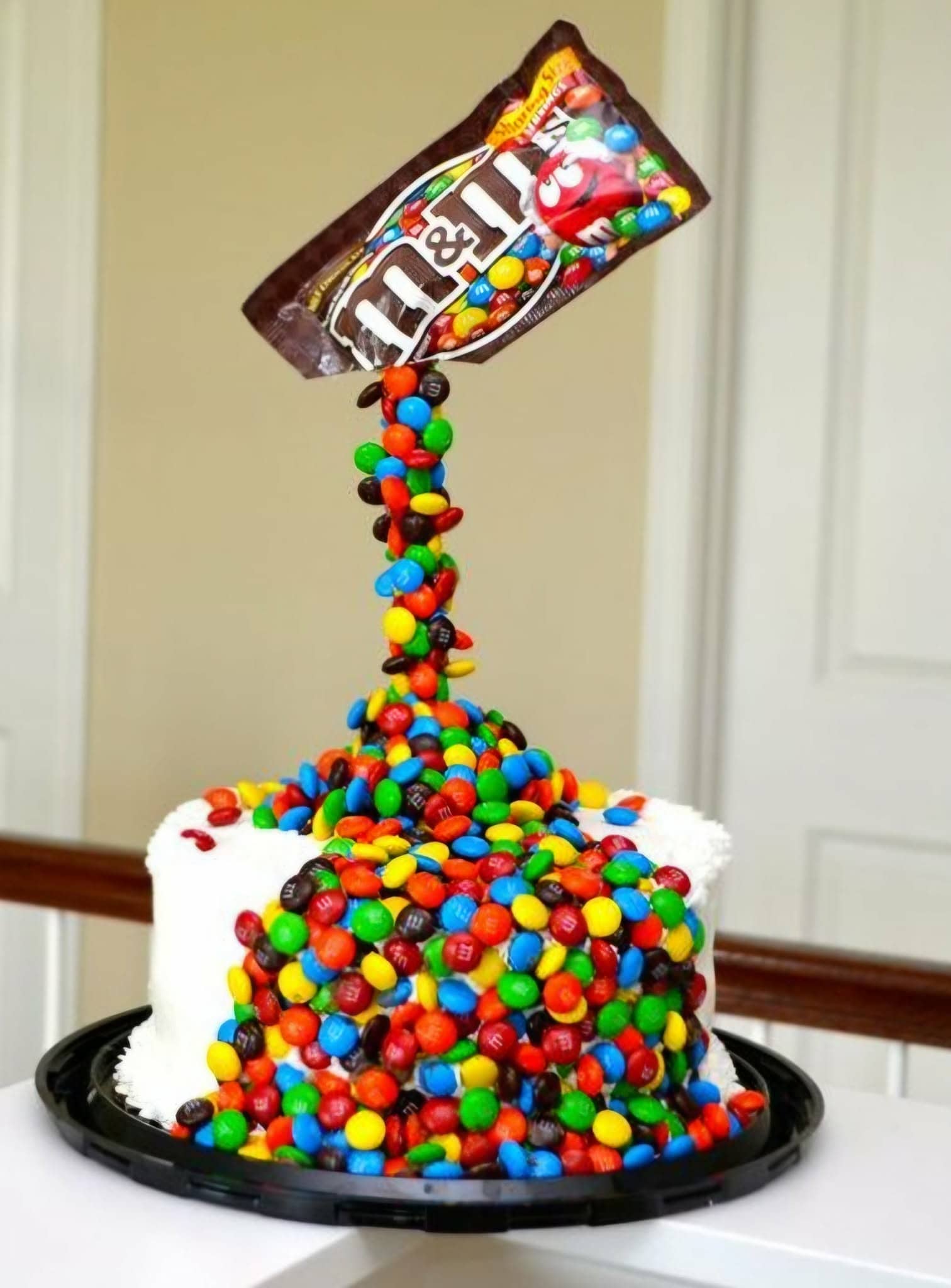 Delicious chocolate cake topped with colorful M&Ms, with a bag of M&Ms pouring over the sides, creating a vibrant and fun dessert perfect for celebrations.