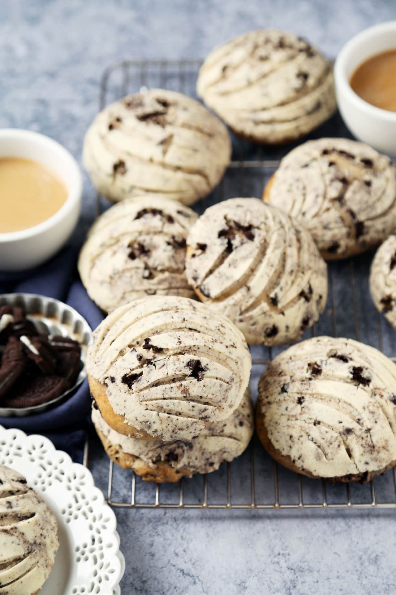Delicious chocolate chip cookie sandwiches filled with vanilla frosting, served with cups of coffee on a cooling rack. Perfect for dessert or snack.