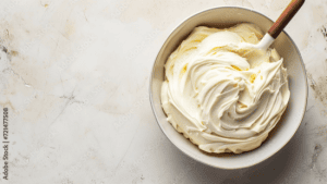 Creamy vanilla buttercream frosting in a bowl with a spatula, perfect for cake decorating and baking. Ideal for creating beautiful, smooth cake layers and intricate designs.