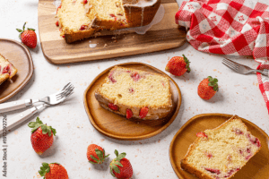 Delicious homemade strawberry bundt cake with fresh strawberries, served on wooden plates with scattered strawberries, perfect for cake decorating and baking supplies.