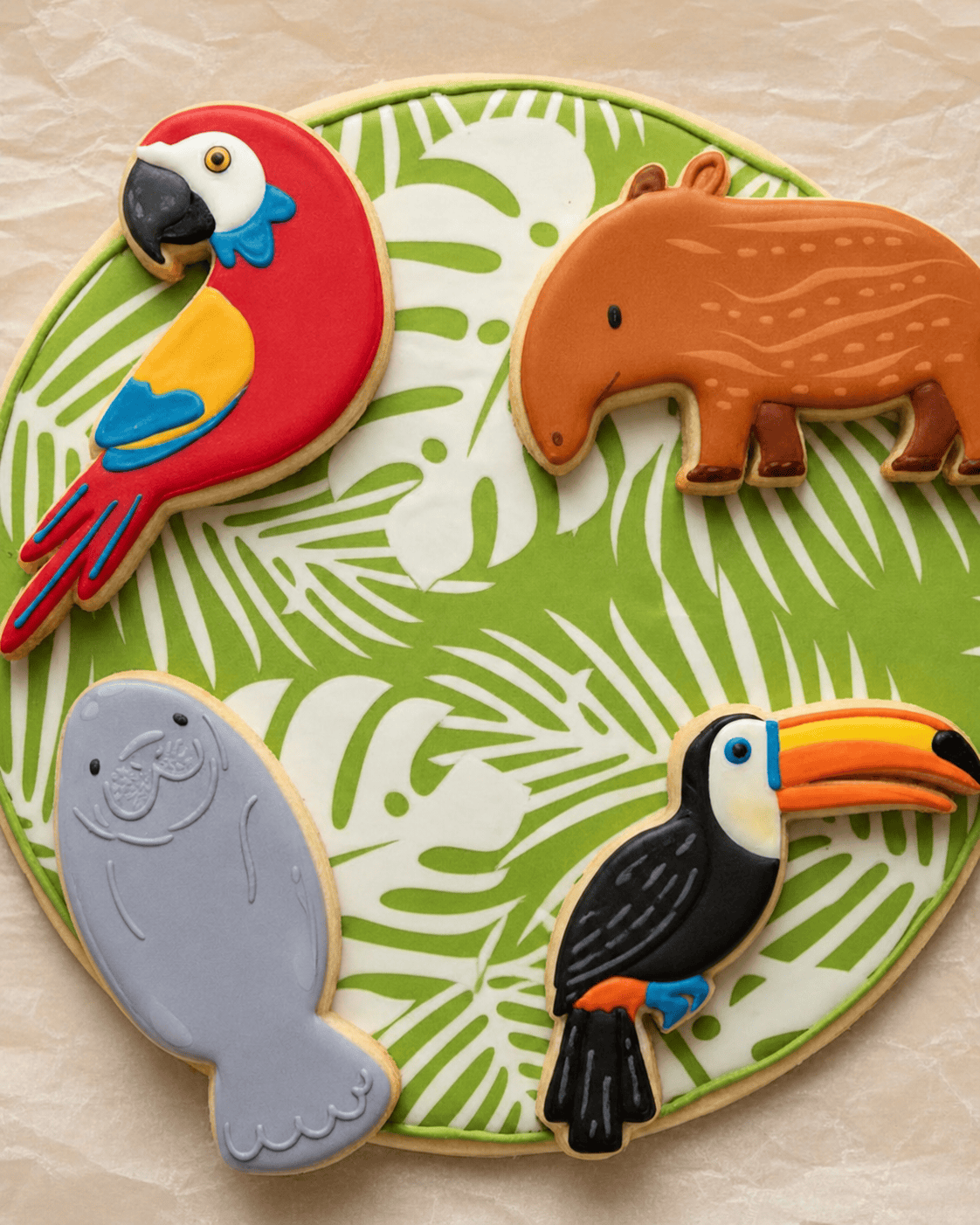 Colorful tropical animal cookies including a parrot, tapir, seal, and toucan, decorated with vibrant icing, perfect for kids camp themed treats.