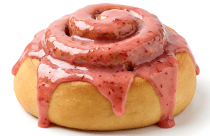 Fresh cinnamon roll topped with strawberry glaze, showcasing a soft, golden-brown pastry with a sweet, fruity topping. Perfect for bakery and cake decorating supplies.