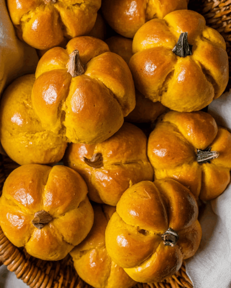 Mini Pumpkin Dinner Rolls for Fall Close-up of small, golden pumpkin-shaped dinner rolls with shiny glaze, perfect for autumn meals and festive gatherings.