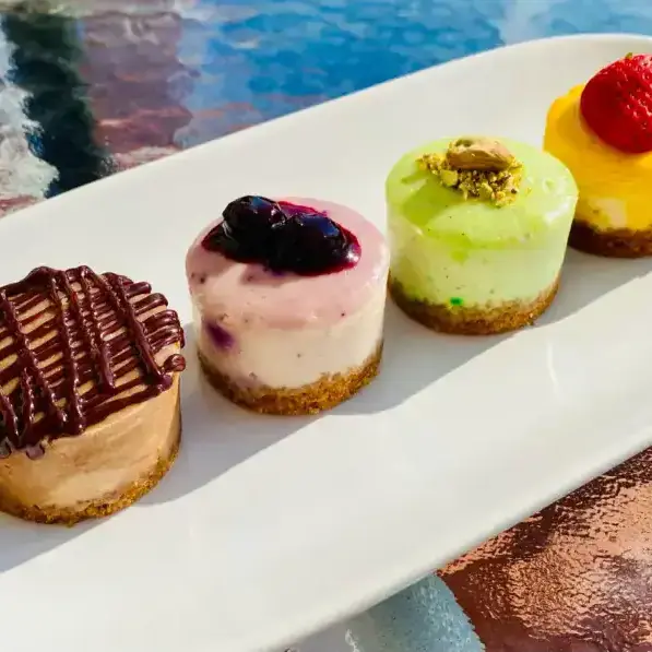 Delicious mini cheesecakes with chocolate, berry, pistachio, and strawberry toppings, perfect for dessert or special occasions from Over the Top Cake Supplies.