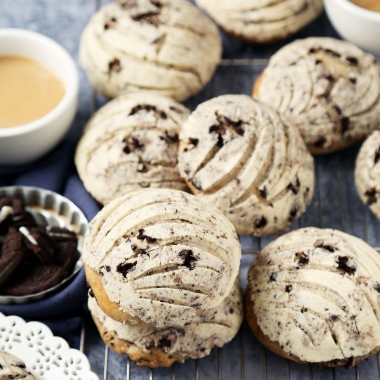 Delicious chocolate chip cookie sandwiches filled with vanilla frosting, served with cups of coffee on a cooling rack. Perfect for dessert or snack.