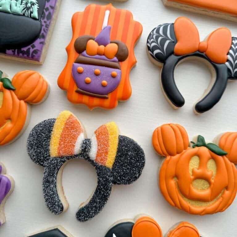 Colorful Halloween-themed decorated cookies including pumpkins, witches, bats, and themed headbands from Over the Top Cake Supplies for festive celebrations.
