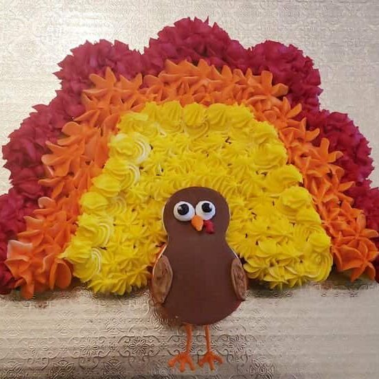 Colorful flower cupcake rainbow with turkey decoration for Thanksgiving cake topper, decorated with vibrant buttercream blooms and a cute edible turkey figure, perfect for festive celebrations.