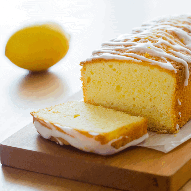 Lemon cake loaf with lemon glaze on wooden board, fresh lemon in background, perfect for cake decorating and baking supplies.