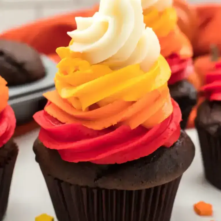 Colorful rainbow cupcake with dark chocolate base and swirled creamy frosting, perfect for birthday celebrations and baking supplies from Over the Top Cake Supplies.