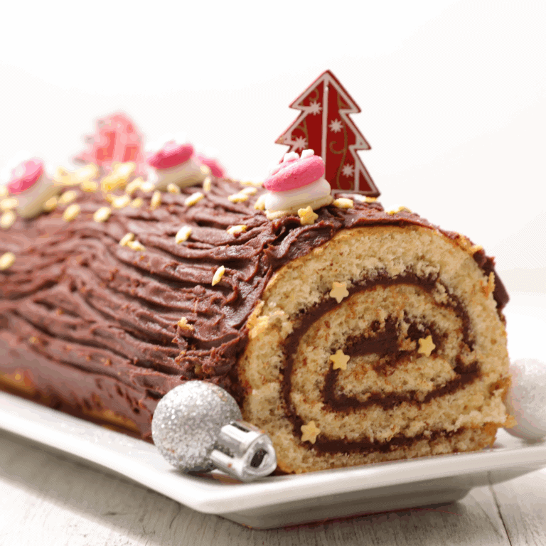 Decorated Christmas yule log cake with chocolate frosting, pink and white fondant accents, edible star sprinkles, and holiday-themed cake topper, on a white serving platter.